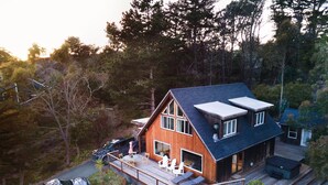 Une maison moderne en bois, dotée d’une grande terrasse, d’un garage et d’un véhicule garé à l’extérieur.