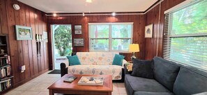 Ein gemütliches Wohnzimmer mit Holzwänden, einer Couch, einem Couchtisch und einem Bücherregal.