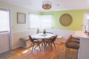 Un espace repas comprenant une table ronde, des chaises, un banc et un comptoir de bar.