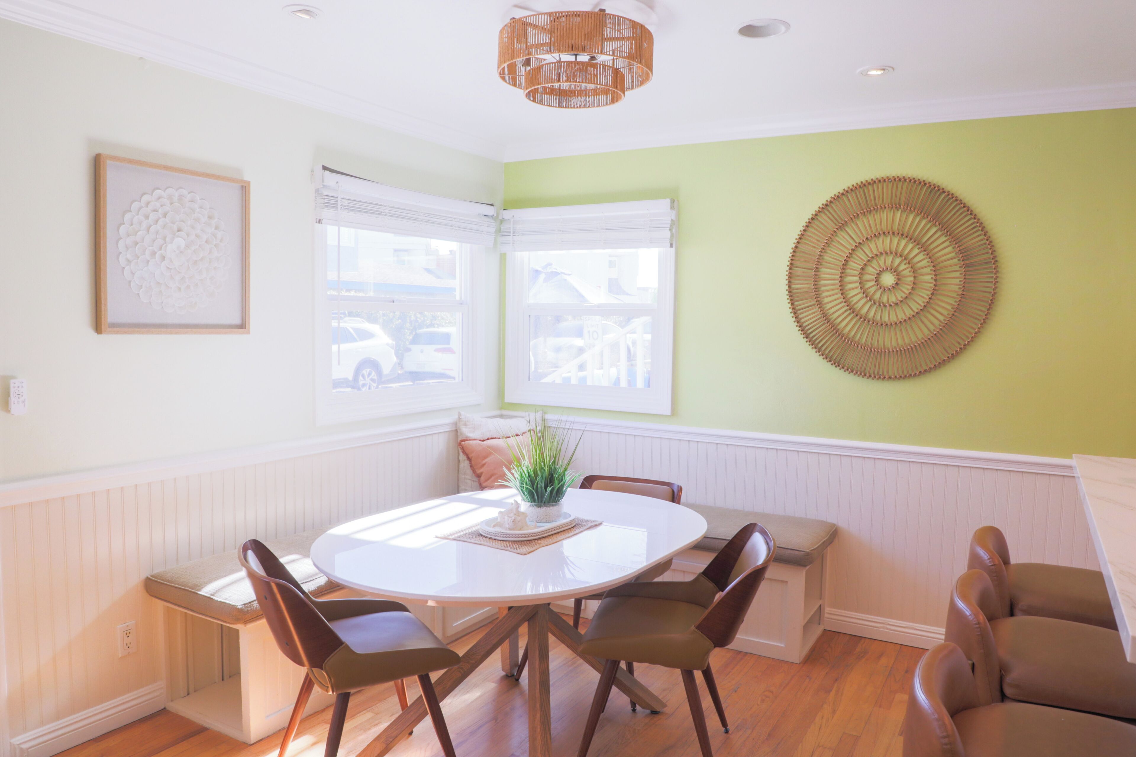 A dining area with a round table, chairs, a plant, and a wall-mounted decorative item.