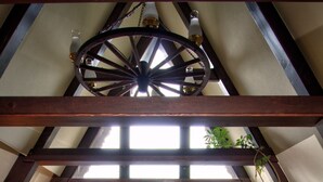Una camera da letto mansardata accogliente, con un'ampia finestra, una poltrona rossa, una pianta pensile e una trave in legno al soffitto.