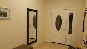 A hallway with two white doors, one with a glass panel, and a large mirror on the left.