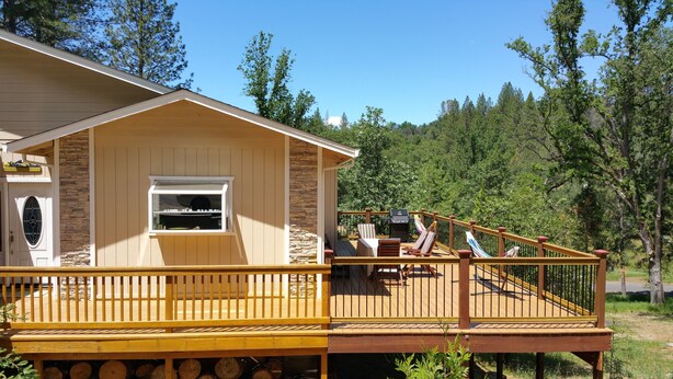 A cabin with a deck, a stone accent wall, and a window.