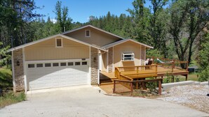 A single-story house with a garage, a deck with outdoor seating, and a stone facade.