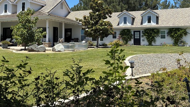 A row of white houses with grey roofs, a grassy lawn, and trees. - Lux Vineyard Escapes- Hilltop Farmhouse  (Temecula)