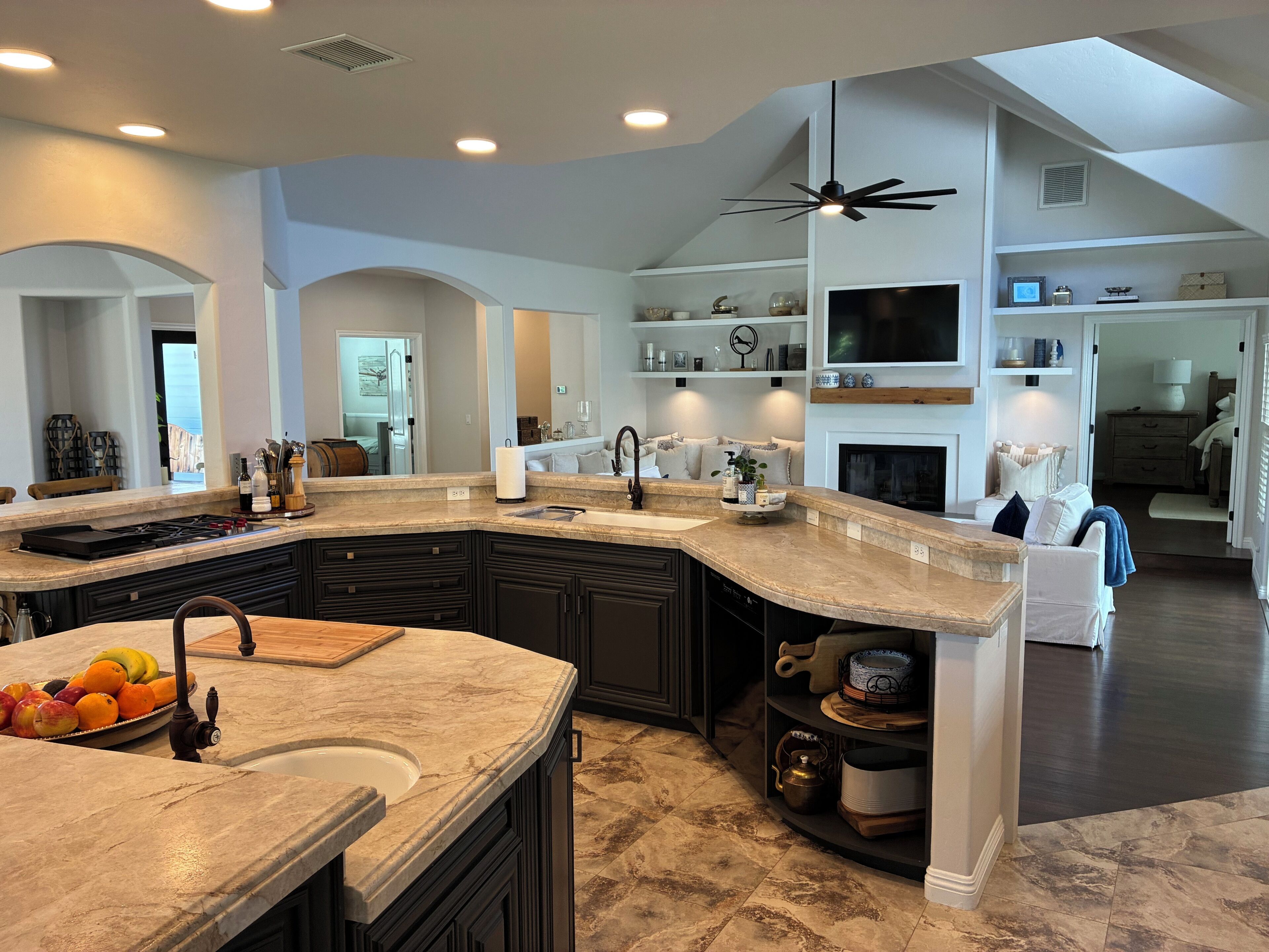 A spacious kitchen with dark cabinetry, a large island, and a ceiling fan.