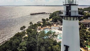 A lighthouse with a clear view of the sea and a pier extending into the water. - King & Prince Oceanfront North Villa (St Simons Island)