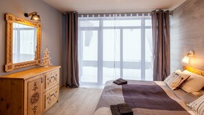 A bedroom with a large bed, wooden dresser, and a mirror.