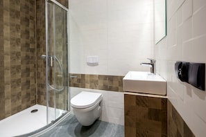 A modern bathroom with a glass shower enclosure, a white toilet, and a sink with a mirror. - Tatrzański Ogród (Zakopane)