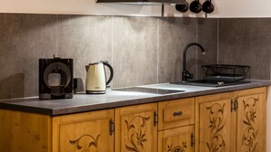 A kitchen with a coffee maker, kettle, and sink.