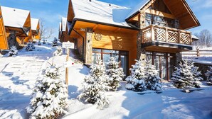 A wooden lodge with a stone facade, multiple windows, and a balcony with lattice work.