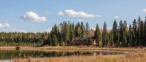 Une cabane au bord d’un lac, entourée d’arbres.