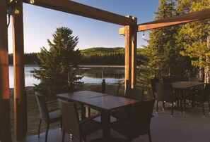 A wooden deck with a table and chairs overlooking a lake and forest. - Schott’s Lake Conference & Resort (Sundre)