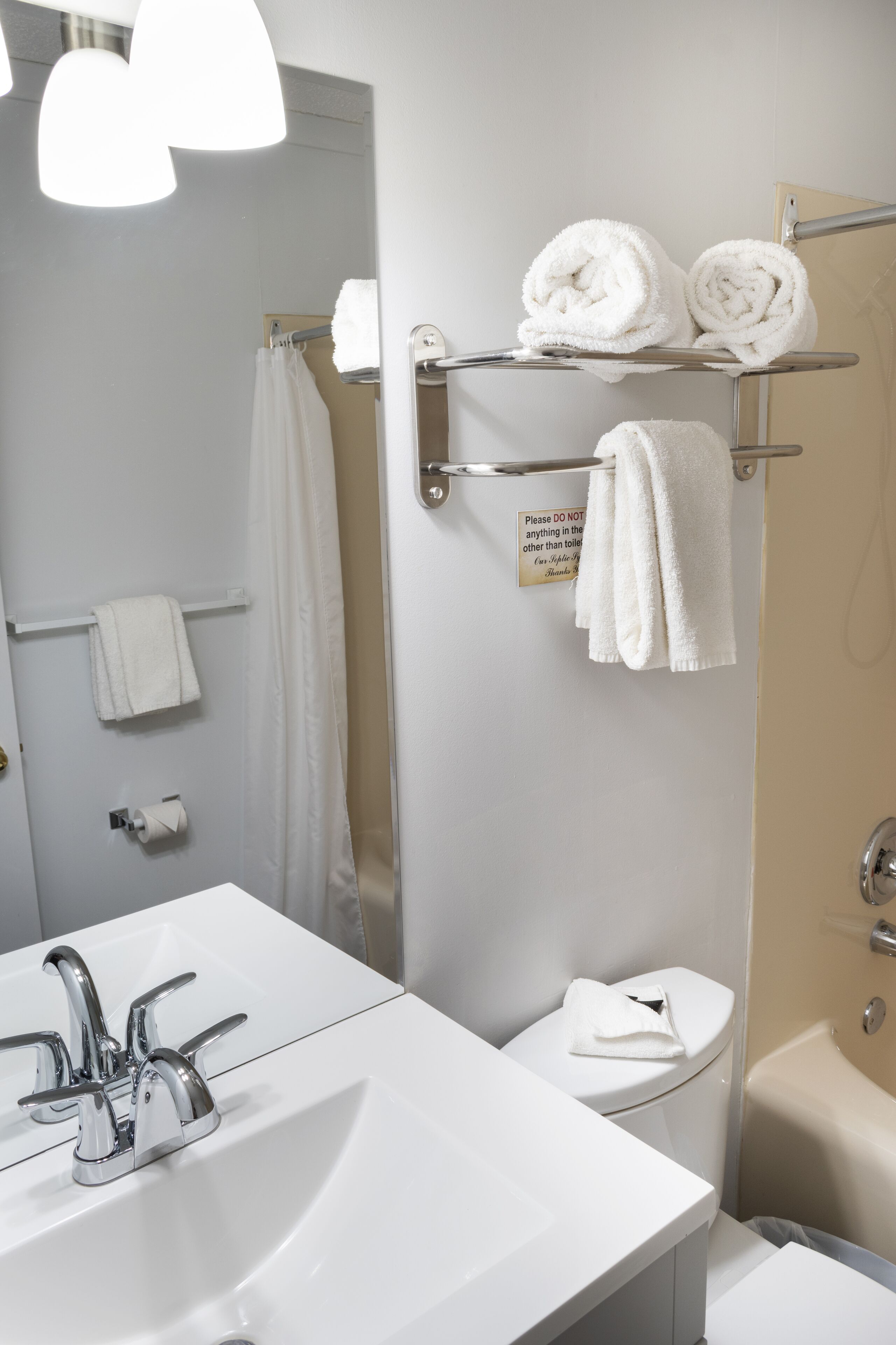 A bathroom with a white sink, a toilet, a shower, and a towel rack with towels.