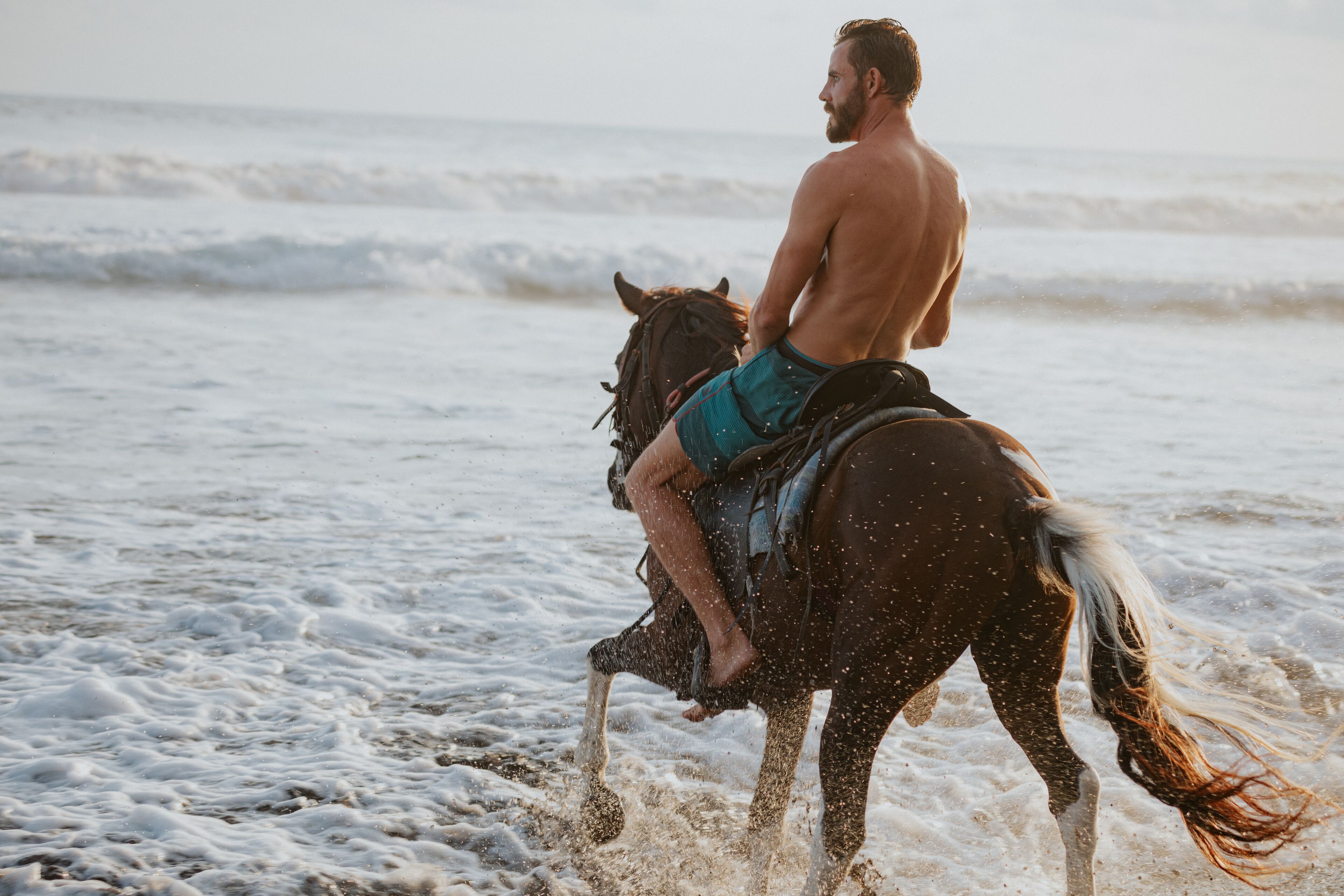 A person riding a horse on a beach with waves.