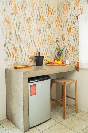 A kitchen with a built-in refrigerator, a wooden stool, and a fruit bowl on the counter.