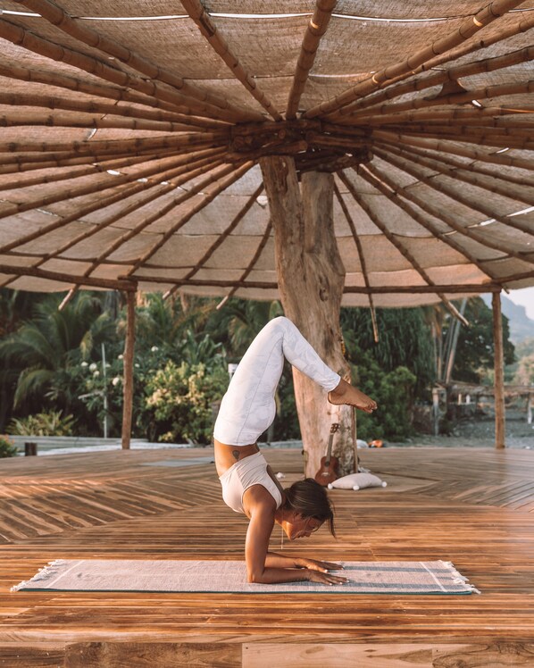 A person performing a handstand under a bamboo structure.