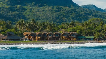 Guests can enjoy stunning ocean views from their thatched-roof bungalow.