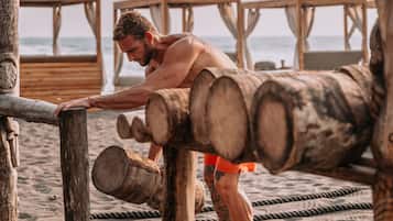 Un hombre haciendo ejercicio en una estructura de madera en la playa.