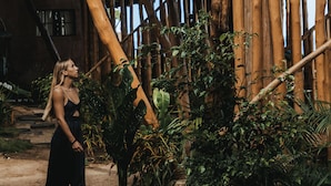 Una estructura rústica de madera con techo de paja, rodeada de abundante vegetación y un sendero de tierra.