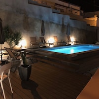 Una piscina al aire libre, sombrillas, sillones reclinables de piscina