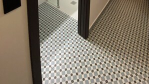 Ein modernes Badezimmer mit Dusche, Toilette und Waschbecken. Der Boden ist mit einem Schachbrettmuster ausgelegt.