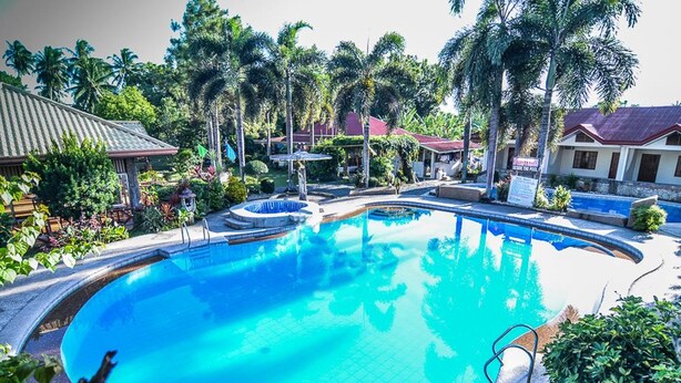 A swimming pool surrounded by palm trees and a building with a red roof. - Zacona Eco-Resort and Biblical Garden (San Pablo)