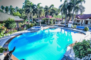 A swimming pool surrounded by palm trees and a building with a red roof. - Zacona Eco-Resort and Biblical Garden (San Pablo)