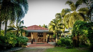 A house with a red roof, surrounded by lush greenery and palm trees. - Zacona Eco-Resort and Biblical Garden (San Pablo)