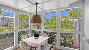 Un solárium con una mesa y sillas, ventanas amplias y un colgador de luz.