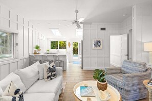 A modern living room with a sofa, striped armchair, and a coffee table with a book and plant.