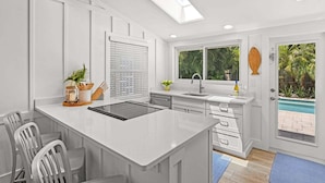 Una cocina moderna con una isla central, electrodomésticos integrados y vistas a una piscina.