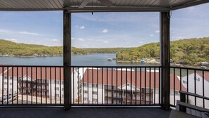 En balkong med utsikt över en sjö, med byggnader i bakgrunden och en takfläkt.