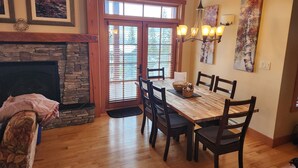 A dining area with a wooden table and chairs, a fireplace, and artwork on the walls. -  Ski-In Ski-Out, Private Hot Tub, Spacious End Unit, Panoramic View (Golden)