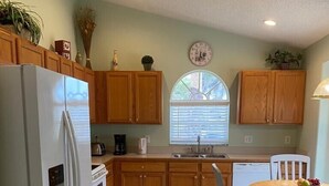 A kitchen with wooden cabinets, a white refrigerator, a sink, and a dining table with chairs. - Last-minute special, NEW beds/AC/pool heater/laminate floor, park view! (Kissimmee)