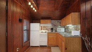 Une cuisine de taille réduite, avec des meubles en bois, un réfrigérateur blanc, une cuisinière, un four à micro-ondes et un grille-pain.