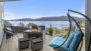 A balcony with wicker furniture, a table with a fruit platter, and a hanging chair. - Quarry Hill Lookout ..... scenic views, luxurious amenities, relaxing atmosphere (Huon Valley)