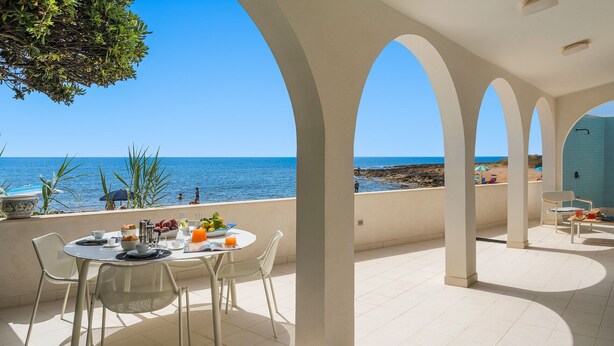 En terrass med ett bord dukat för frukost, med utsikt över havet.