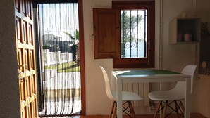 Ein kleiner Essbereich mit Tisch und zwei Stühlen, ein Fenster mit Ausblick und ein Holzschrank darüber.
