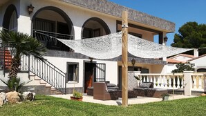 Ein zweigeschossiges Haus mit Balkon, Treppe und gepflegtem Rasen.