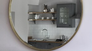 A kitchen with a round mirror, wooden shelves, and a sink. - The Cottage, a romantic getaway (Dunblane)