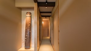 A hallway with a wooden sculpture, a ceiling light, and a textured floor. - Shirasagi Kyoto (Kyoto)