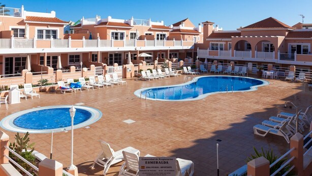 Een zwembadterras van een hotel met diverse ligbedden en een centraal gelegen zwembad.