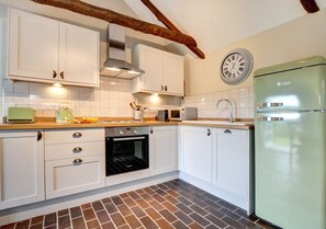 Enjoy cooking in this kitchen with a microwave, refrigerator, and brick-patterned floor.
