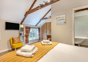 Relax in a spacious room with a large bed, flat-screen TV, and a comfortable armchair.