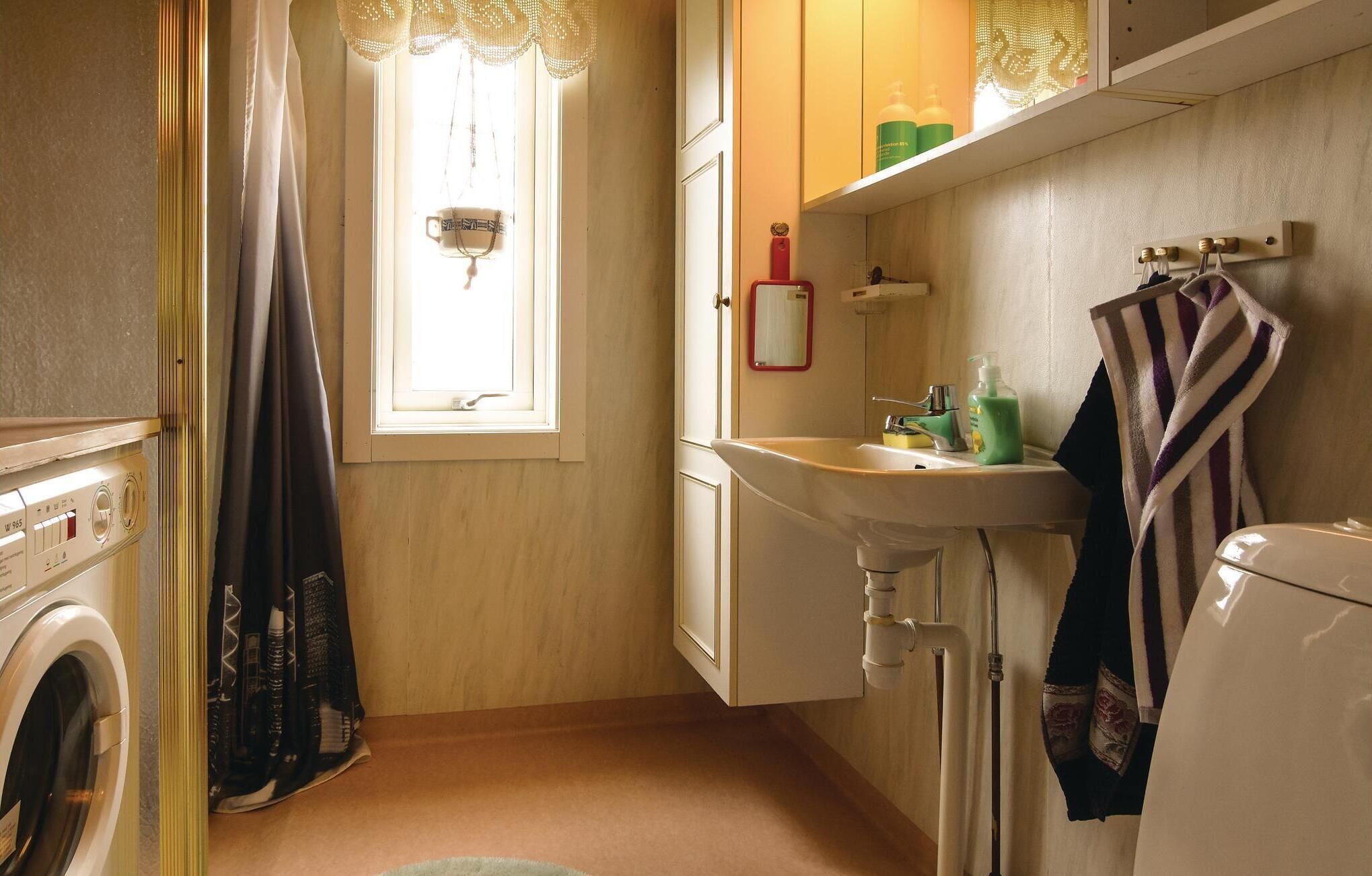 A compact bathroom with a washing machine, a sink, and a toilet.