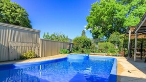 A rectangular swimming pool with a blue interior, surrounded by a white fence and trees. - Ambrosia Holiday Home (Tanunda)