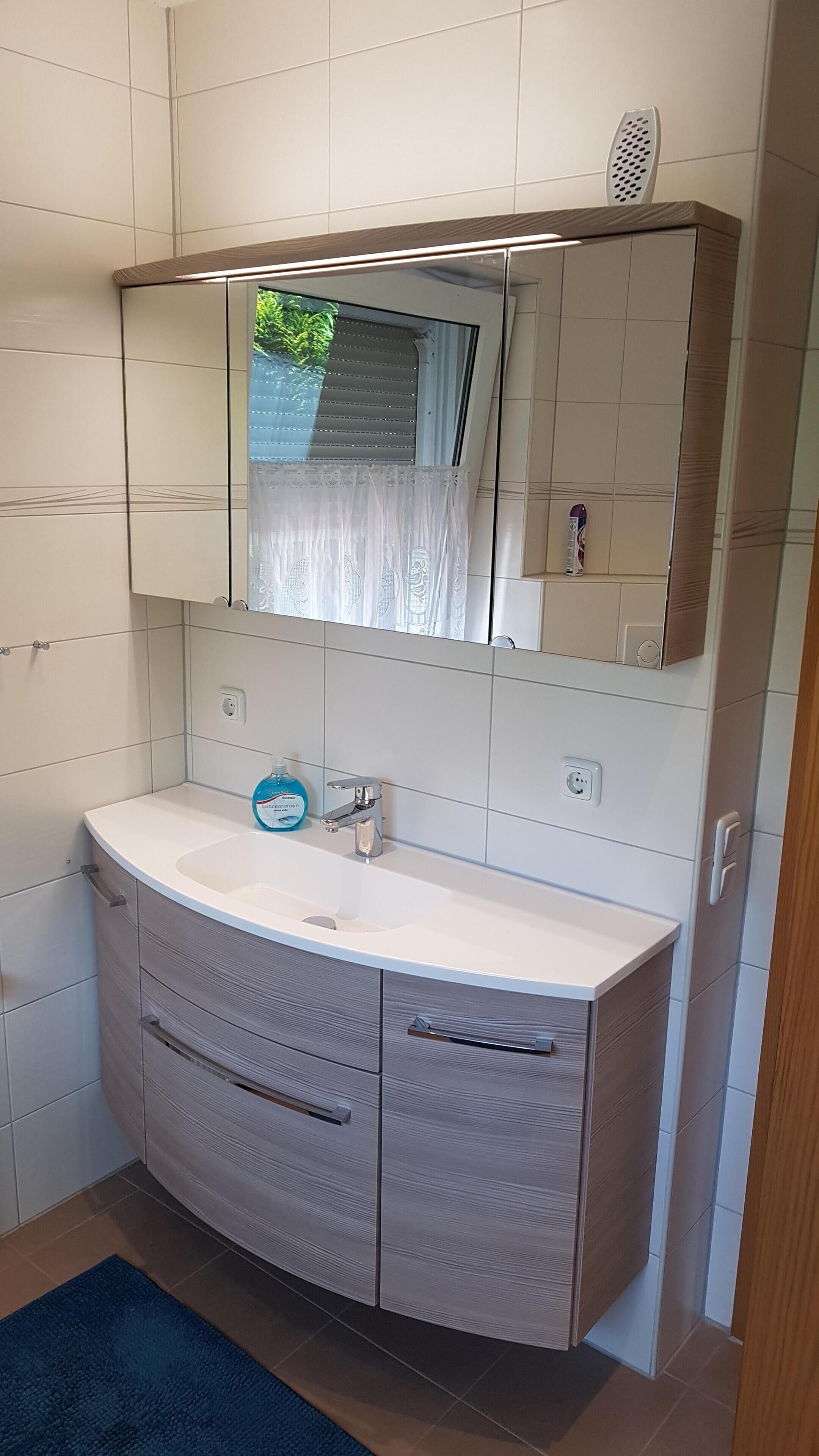A bathroom with a white sink, a mirror, and a cabinet with drawers.