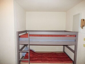 Ein Stockbett mit einer rot gemusterten Decke und einer schlichten Matratze.
