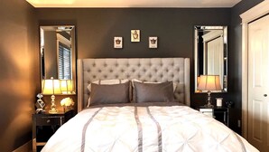 A neatly arranged bedroom with a tufted headboard, two bedside tables with lamps, and framed pictures on the wall. - Perfect couple retreat paradise found at Casa De Luce (Kelowna)